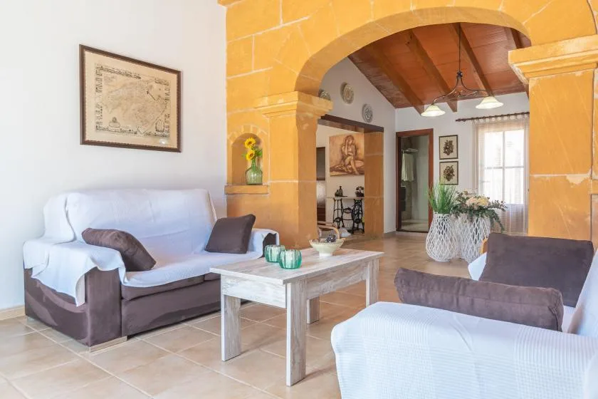 Una sala de estar con asientos y una mesa de centro bajo un gran arco de piedra.