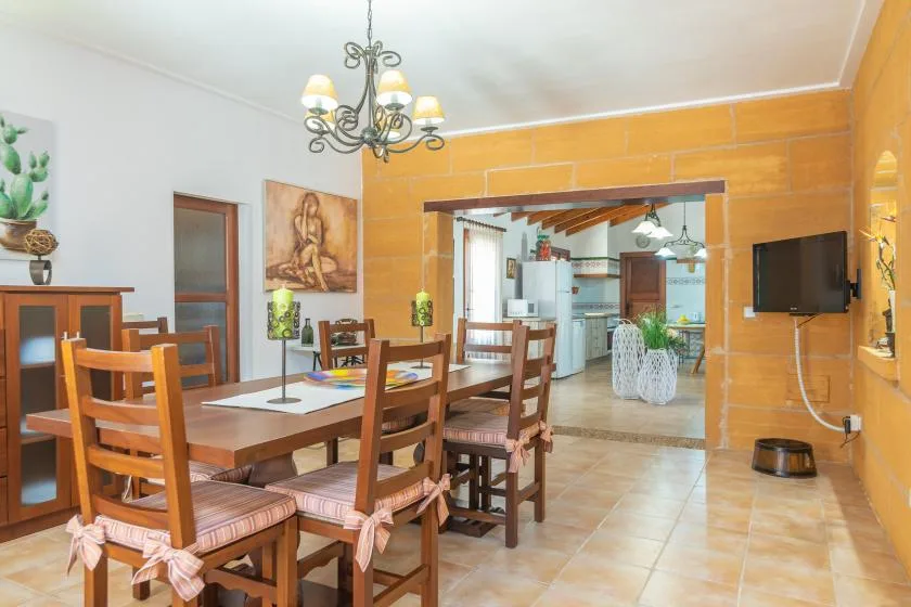 Un comedor con mesa y sillas de madera se abre a una cocina.