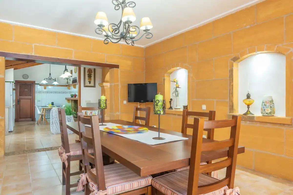 Un comedor con una mesa larga de madera y una lámpara de araña.