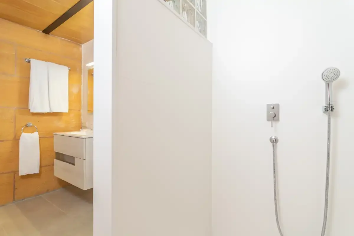 Un baño con una ducha de pared junto a un tocador y toallas.