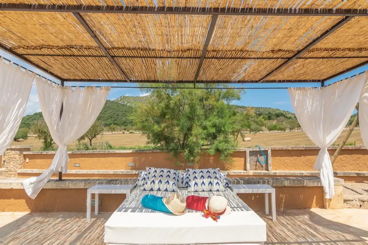 Una zona de descanso exterior a la sombra, con asientos bajos blancos y vistas a las colinas.