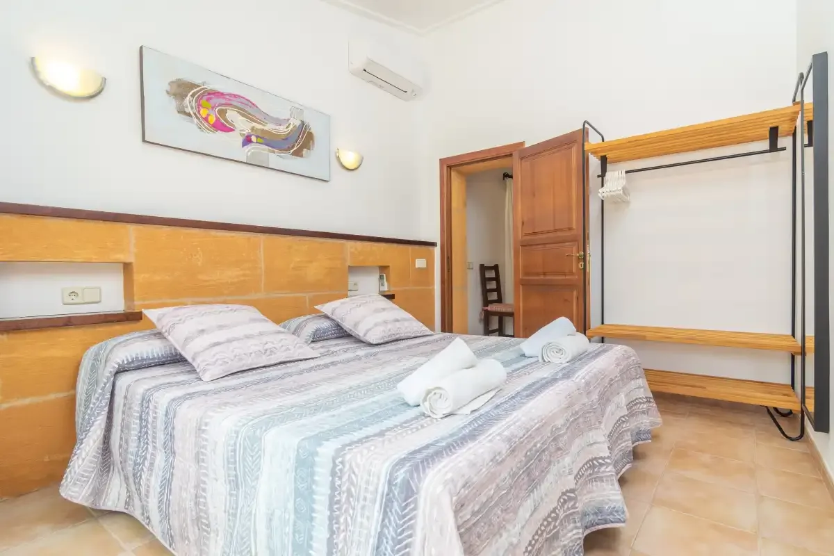 Un dormitorio con una cama doble y un perchero de madera.