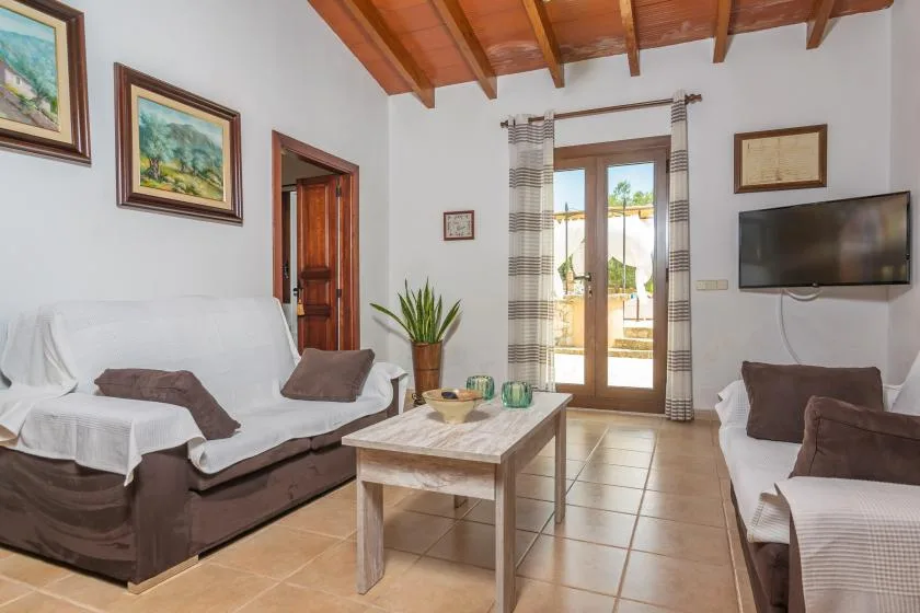 Una sala de estar con asientos, una mesa de centro y puertas de vidrio hacia un patio.