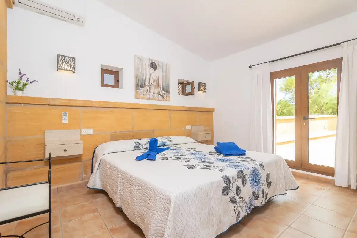 Dormitorio con una cama doble y puertas de cristal que dan a un balcón.