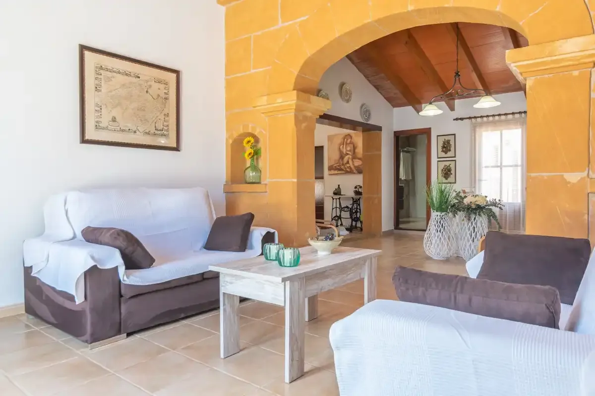 Una sala de estar con asientos y una mesa de centro bajo un amplio arco de piedra.