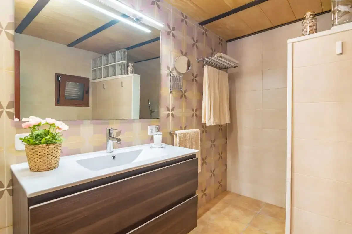 Un baño con lavabo, espejo y zona de ducha.