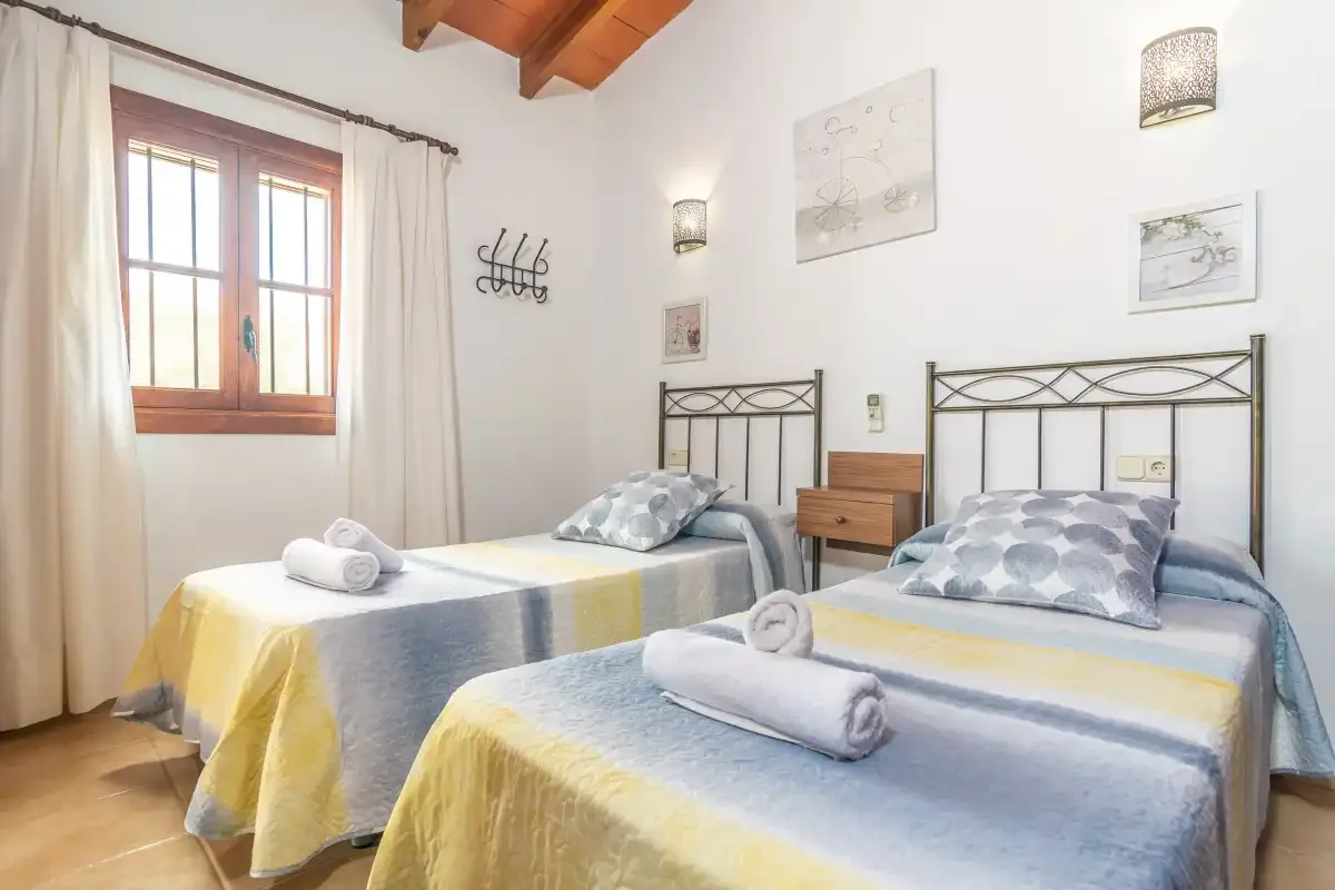 Un dormitorio luminoso con dos camas, ropa de cama estampada y techo de madera.