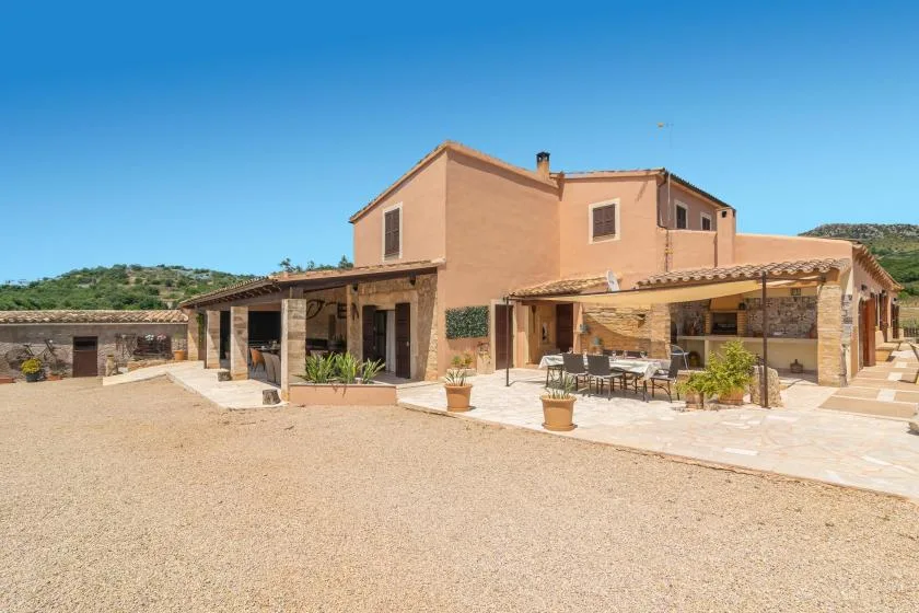 A peach-colored house with a covered patio and outdoor seating beside a gravel courtyard.