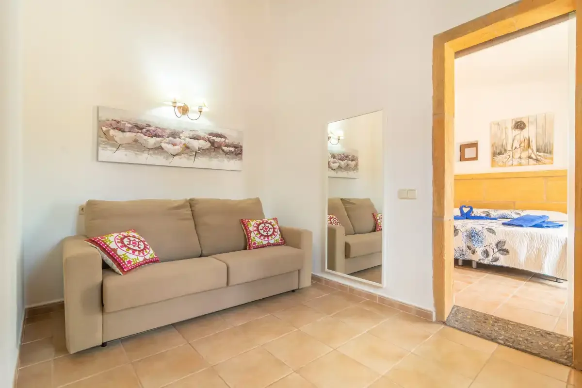 Una sala de estar con un sofá beige y una puerta a un dormitorio.
