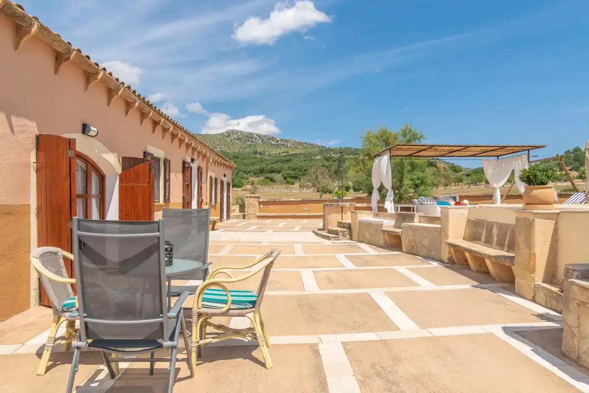 Una terraza exterior soleada con asientos y una zona de comedor con sombra.