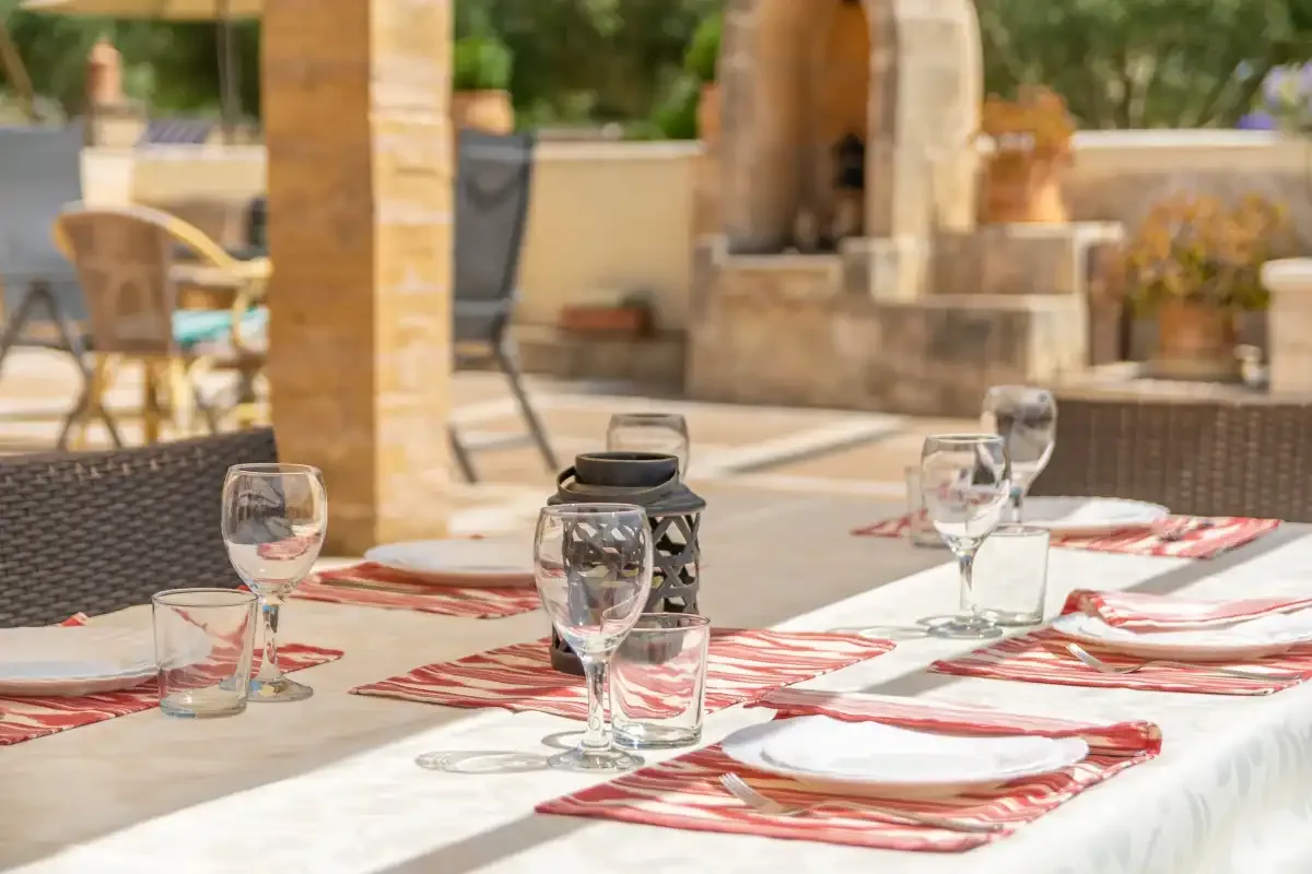 Una mesa de comedor al aire libre está preparada con platos y vasos.