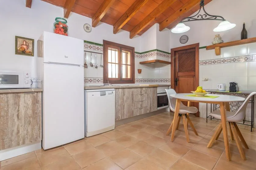 Una cocina luminosa con vigas de madera en el techo y una mesa de comedor.