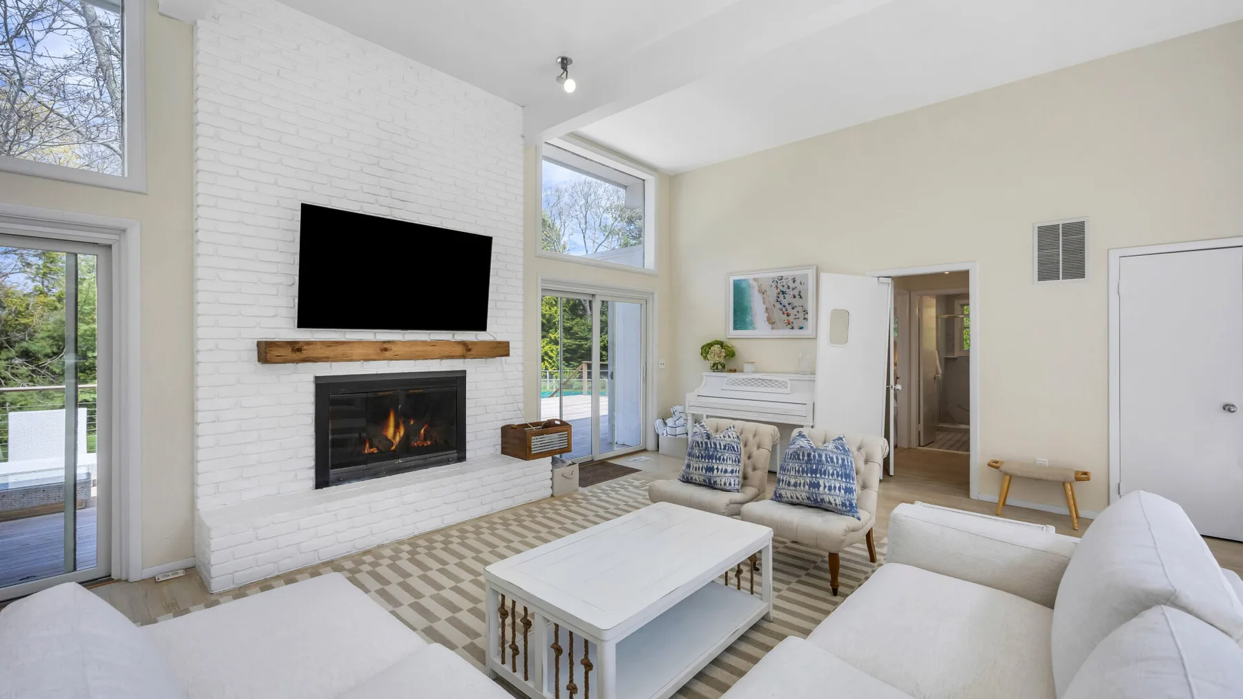 A bright living room with a fireplace, seating, and large windows.
