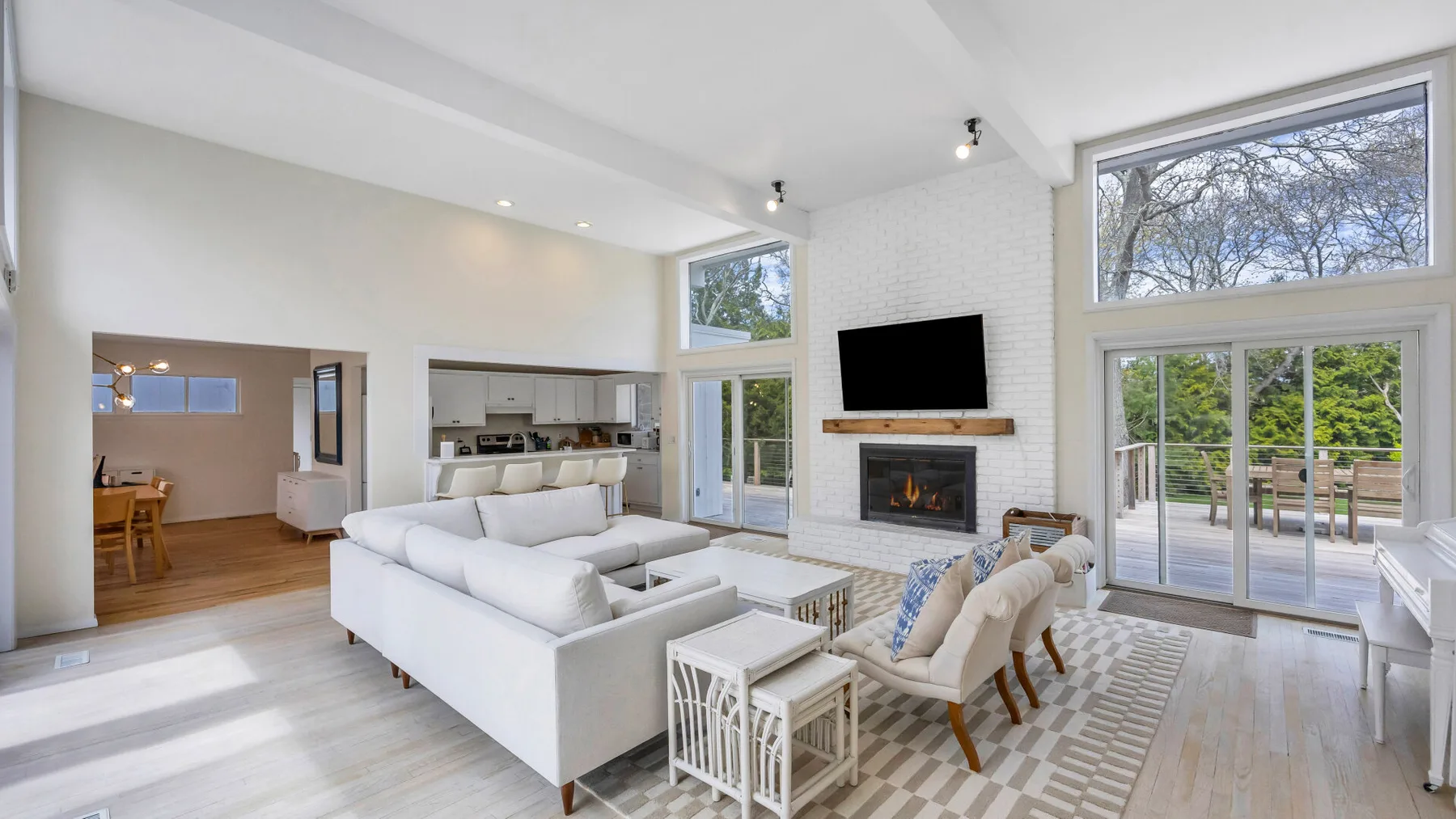 A bright living room with white seating, a fireplace, and large windows.