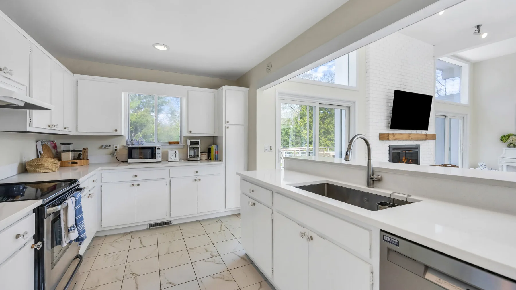 A bright kitchen with white cabinetry, a central island, and a sink.