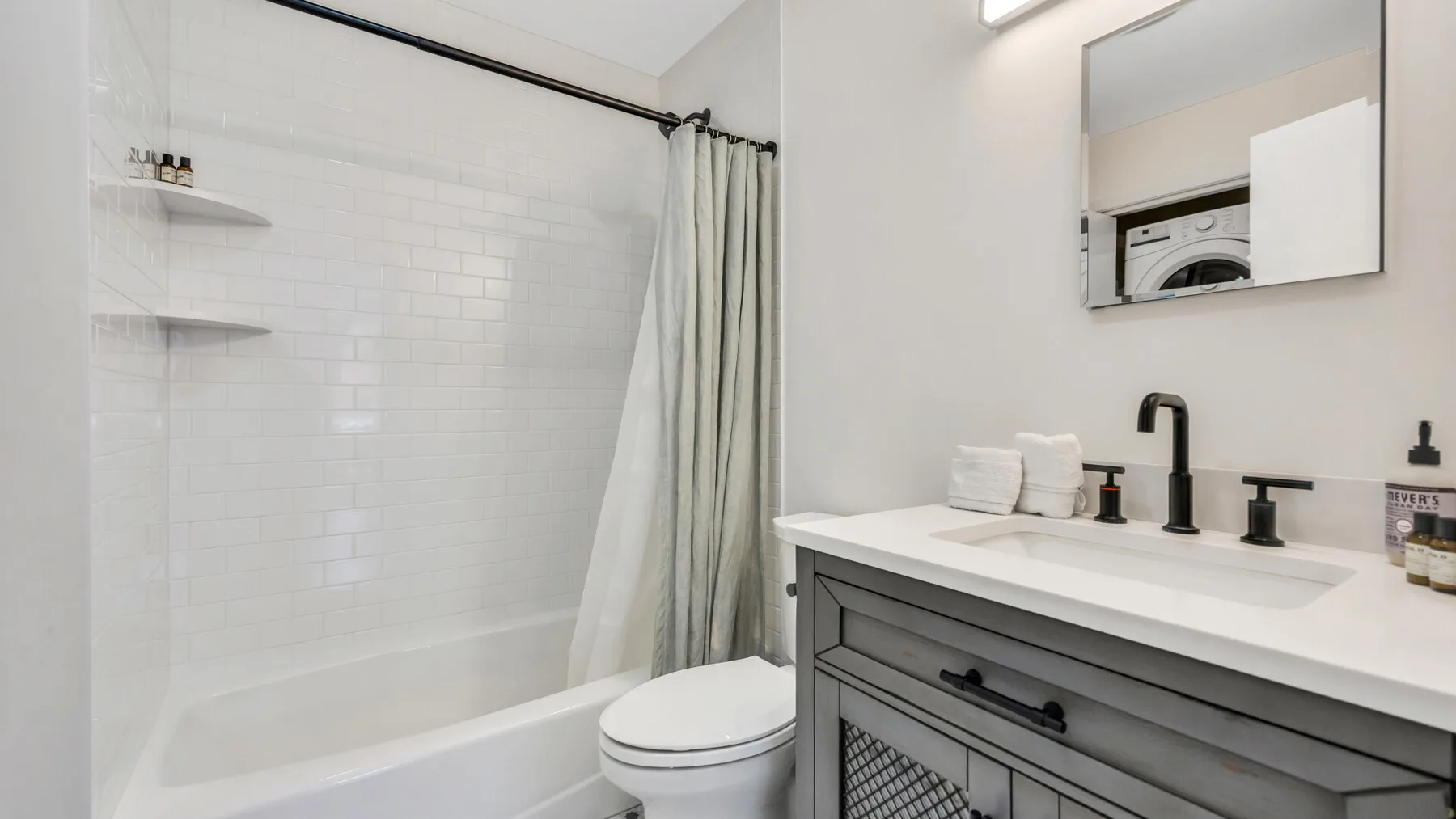 A bright bathroom with a bathtub, shower curtain, and vanity.