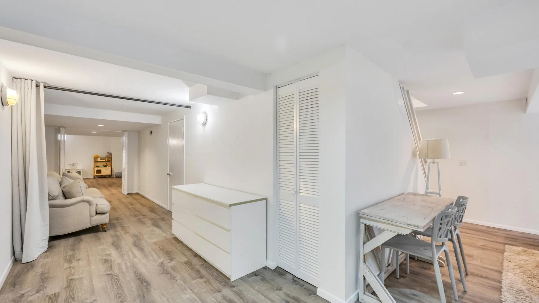 A bright open-plan living and dining area with neutral seating and a dining table.