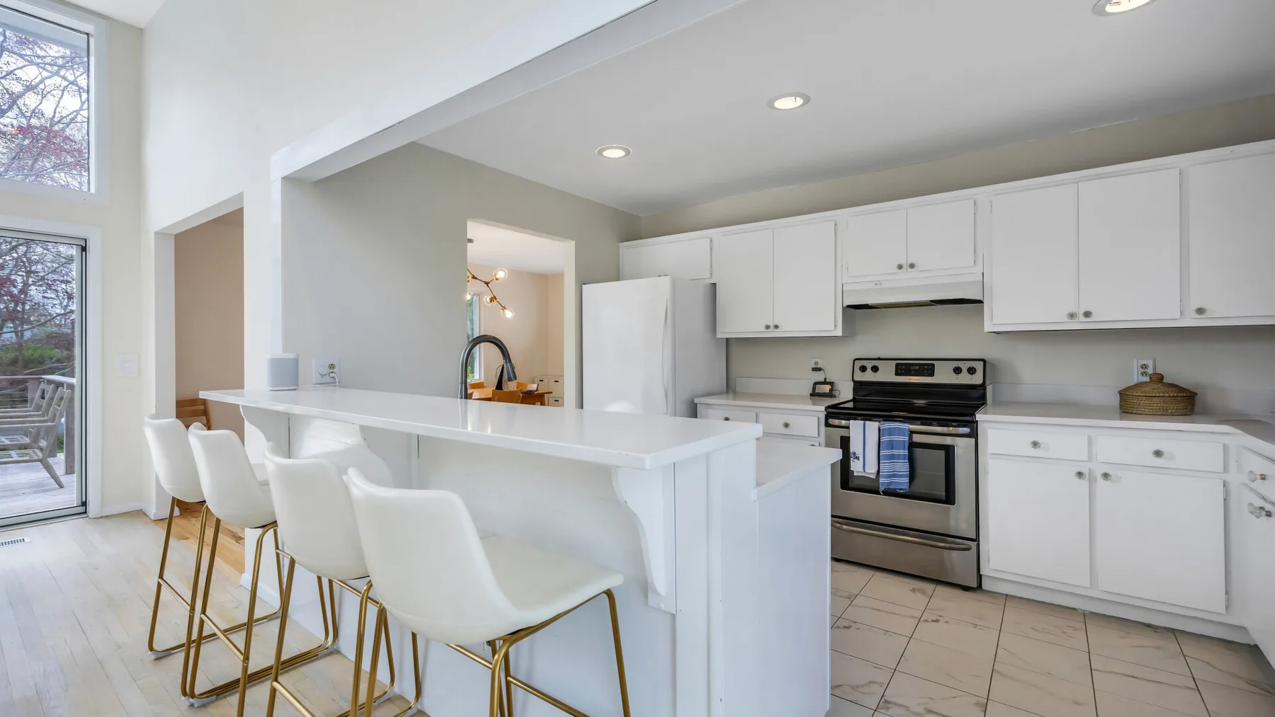 A bright kitchen features white cabinets and a long island with bar seating.