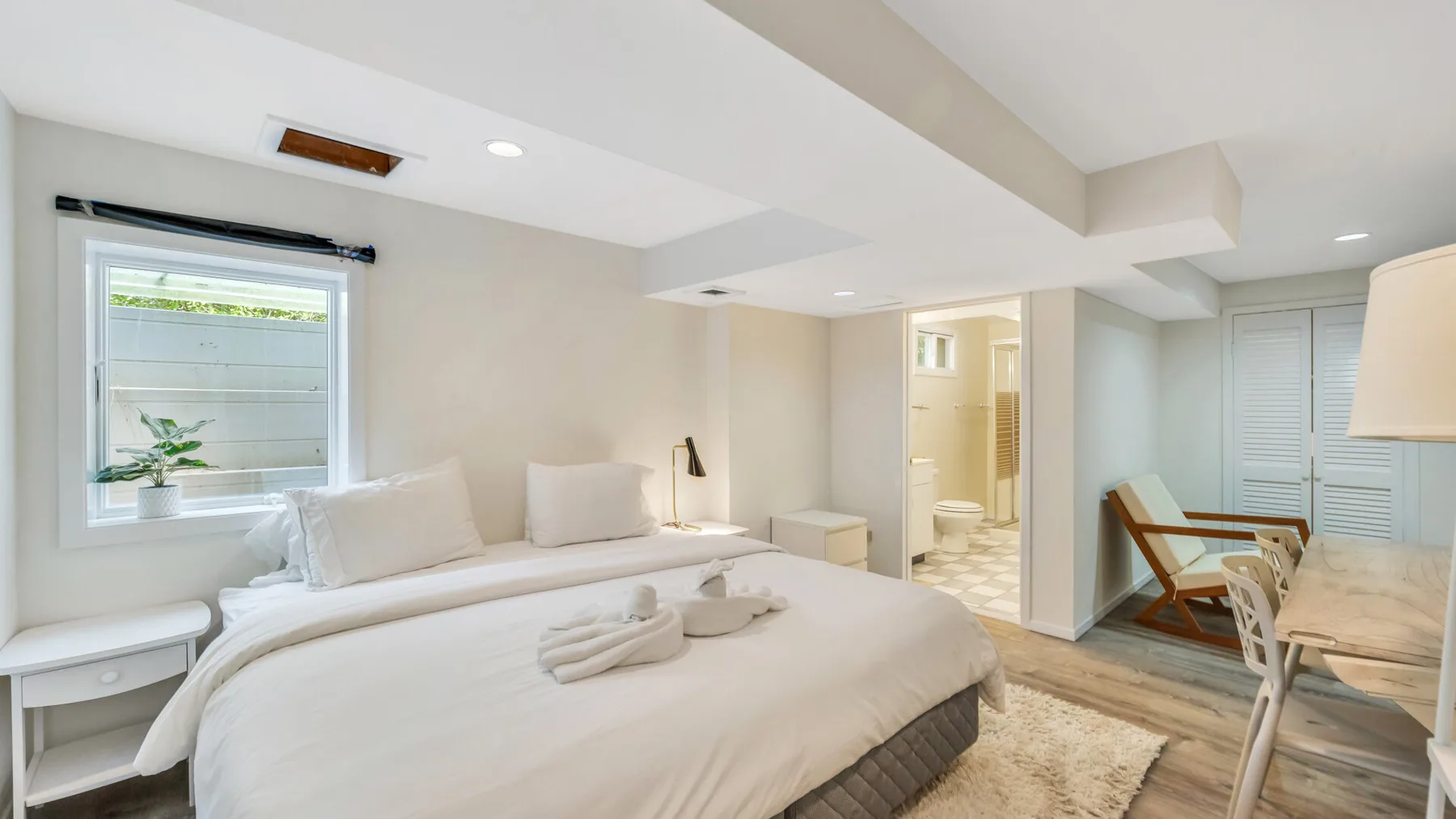 A bright bedroom with a bed, bedside tables, and a window.