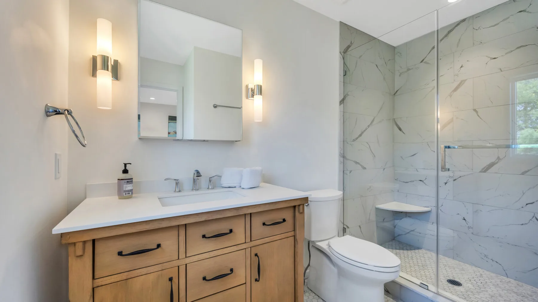 A bathroom with a wood vanity, sink, and glass shower.