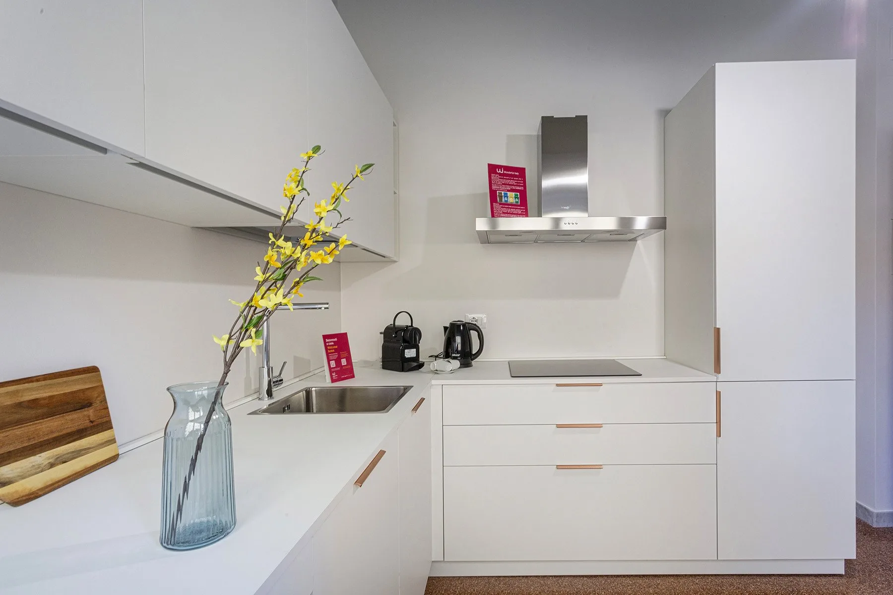 A bright white kitchen with a stainless-steel range hood and countertop appliances.