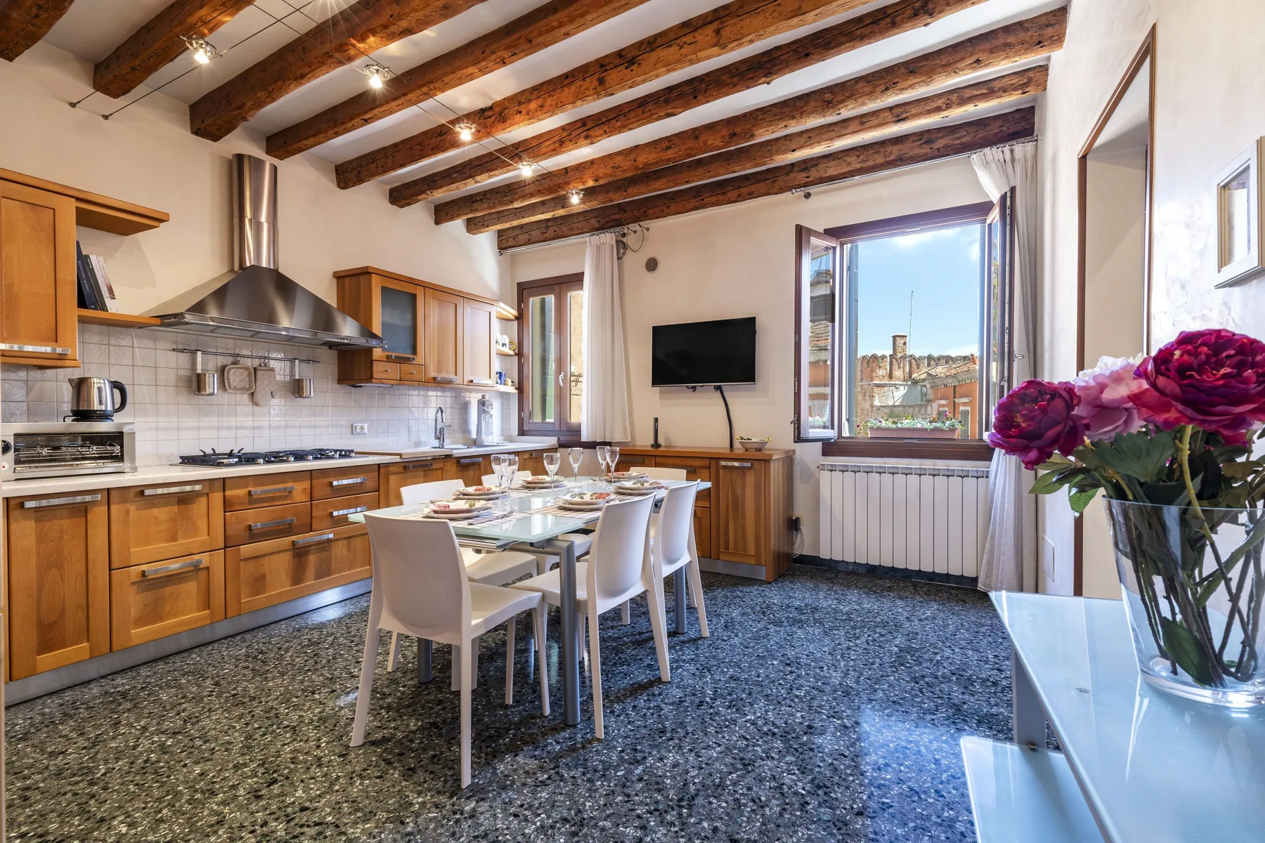 Una cocina y comedor con armarios de madera, una mesa y un televisor.