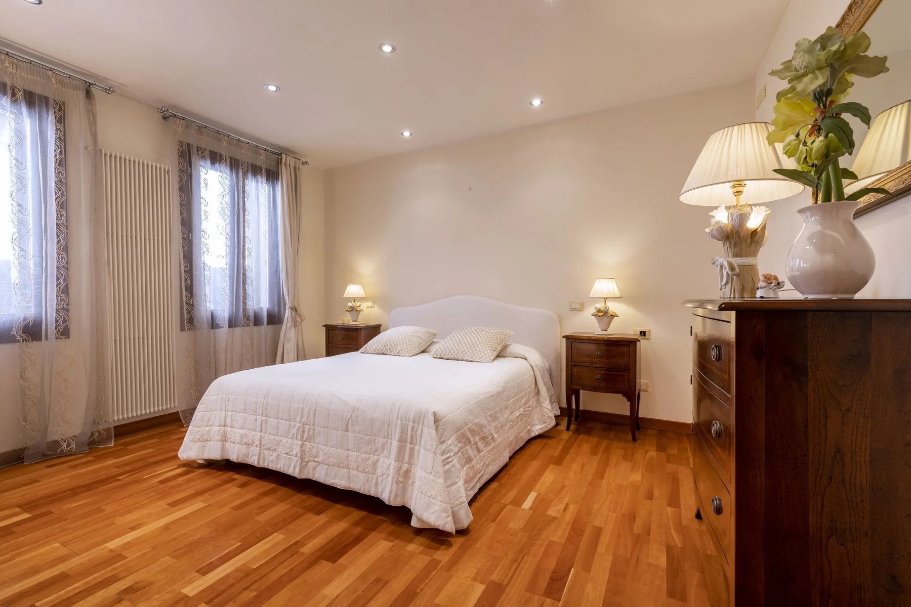 Un dormitorio con una cama bien tendida y suelo de madera cálida.