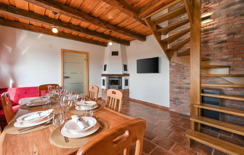 Un comedor con la mesa puesta junto a una escalera de ladrillo y un televisor.