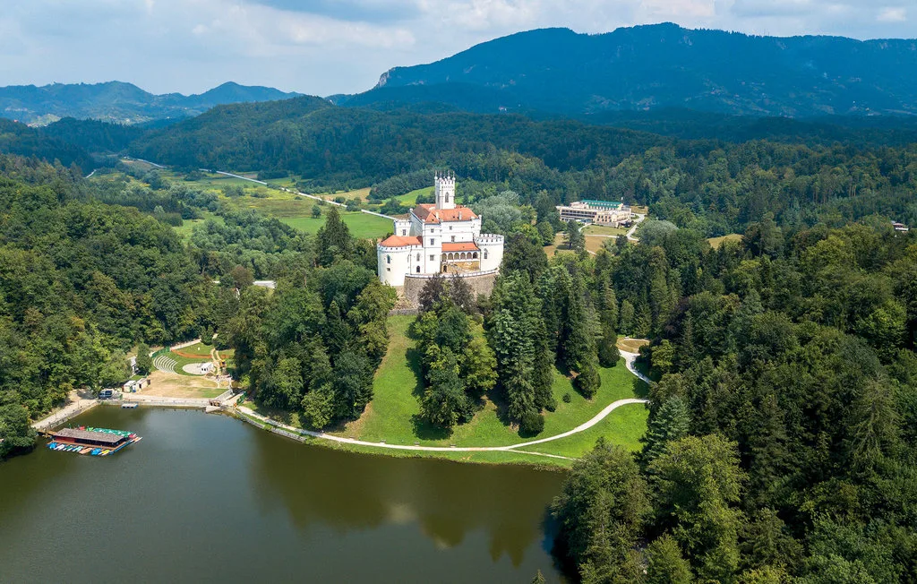 Un castillo domina un lago entre colinas boscosas.