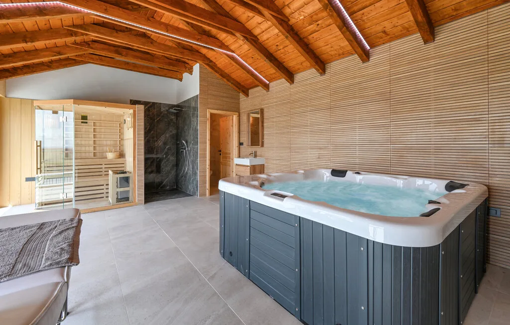 Un espacio de spa con una gran bañera de hidromasaje bajo un techo abovedado de madera.