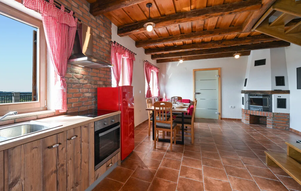 Cocina y comedor con vigas de madera en el techo y una chimenea de ladrillo.