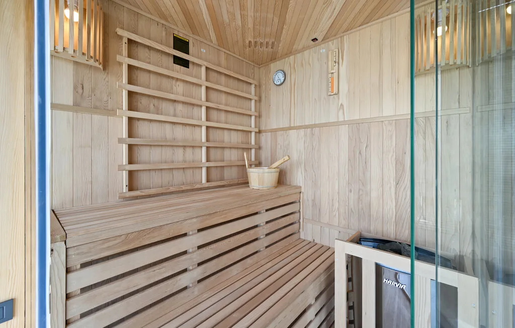 Una sauna revestida de madera, con bancos escalonados y un pequeño reloj.