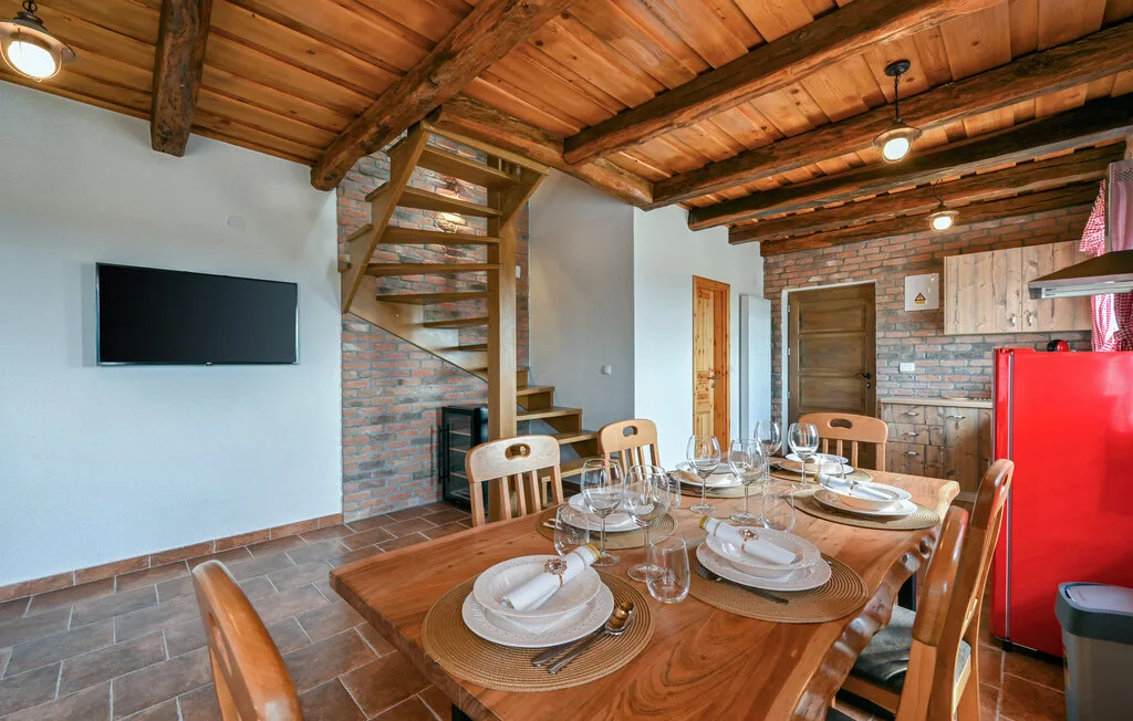 Un comedor con una mesa de madera bajo una escalera y vigas expuestas.