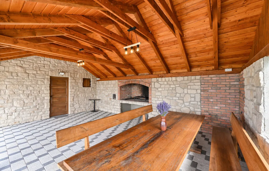Comedor rústico con mesas largas de madera bajo un techo de vigas.