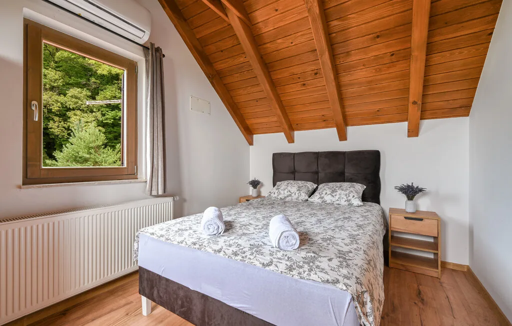 Un dormitorio con una cama doble bajo un techo inclinado de madera.