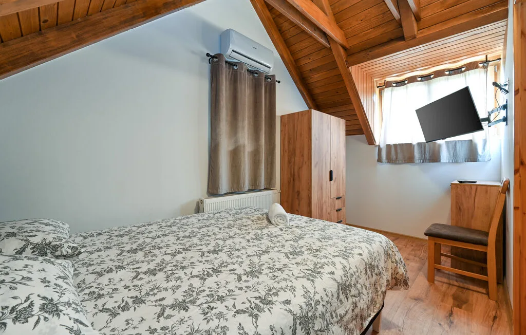 Un dormitorio con una colcha floral, un armario de madera y techo inclinado de madera.