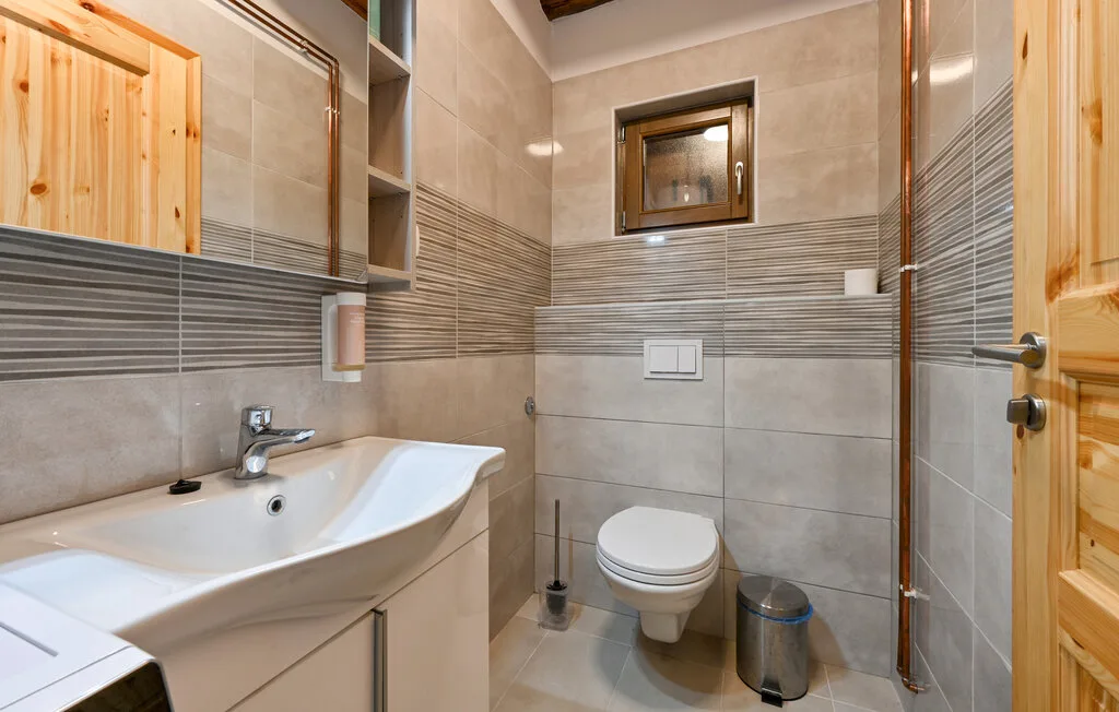 Un baño con azulejos, lavabo, inodoro y una ventana pequeña.