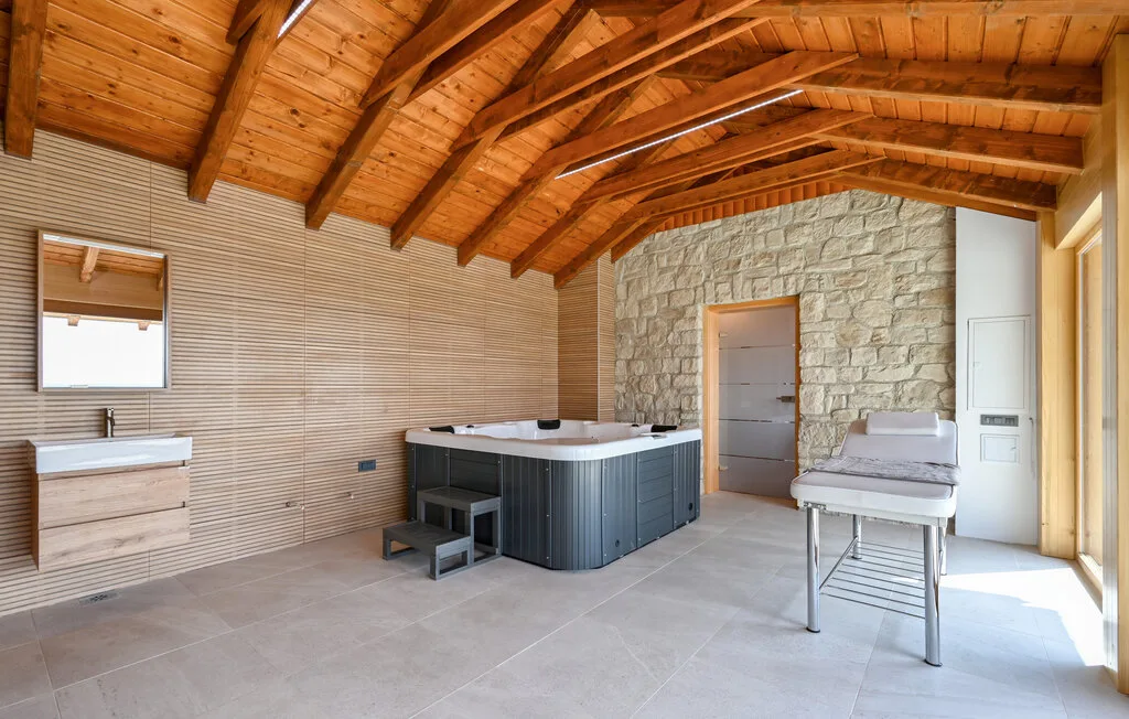 Un spa con una gran bañera de hidromasaje y una camilla de masaje bajo un techo de madera.