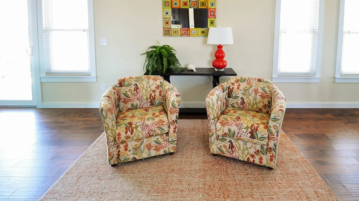 Una zona de estar con asientos estampados frente a una mesa consola.