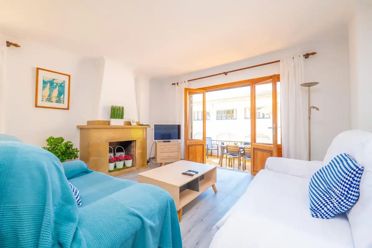Una sala de estar luminosa con asientos alrededor de una mesa de centro y una puerta abierta al balcón.
