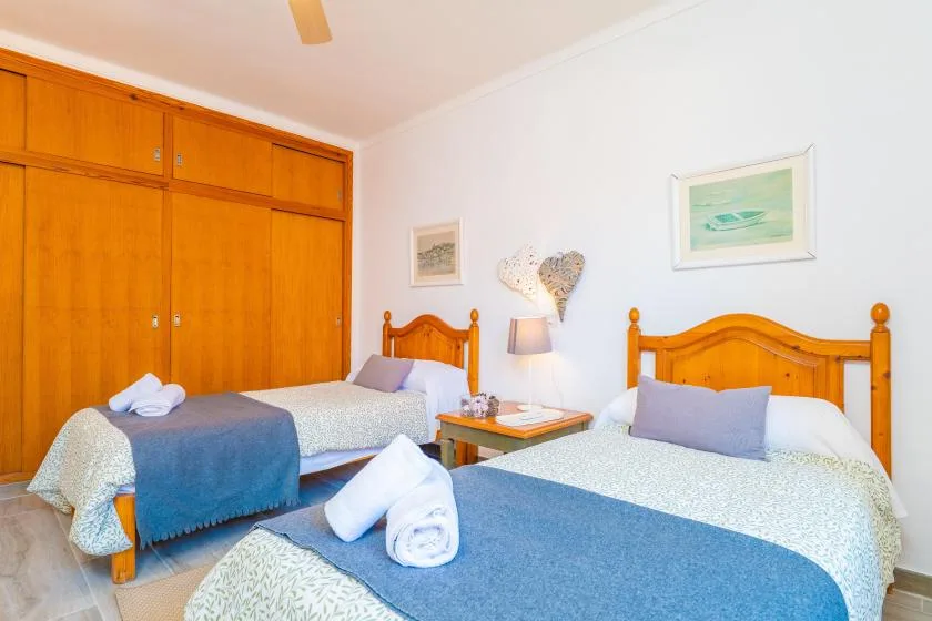 Un dormitorio con dos camas, ropa de cama azul y armarios de madera.