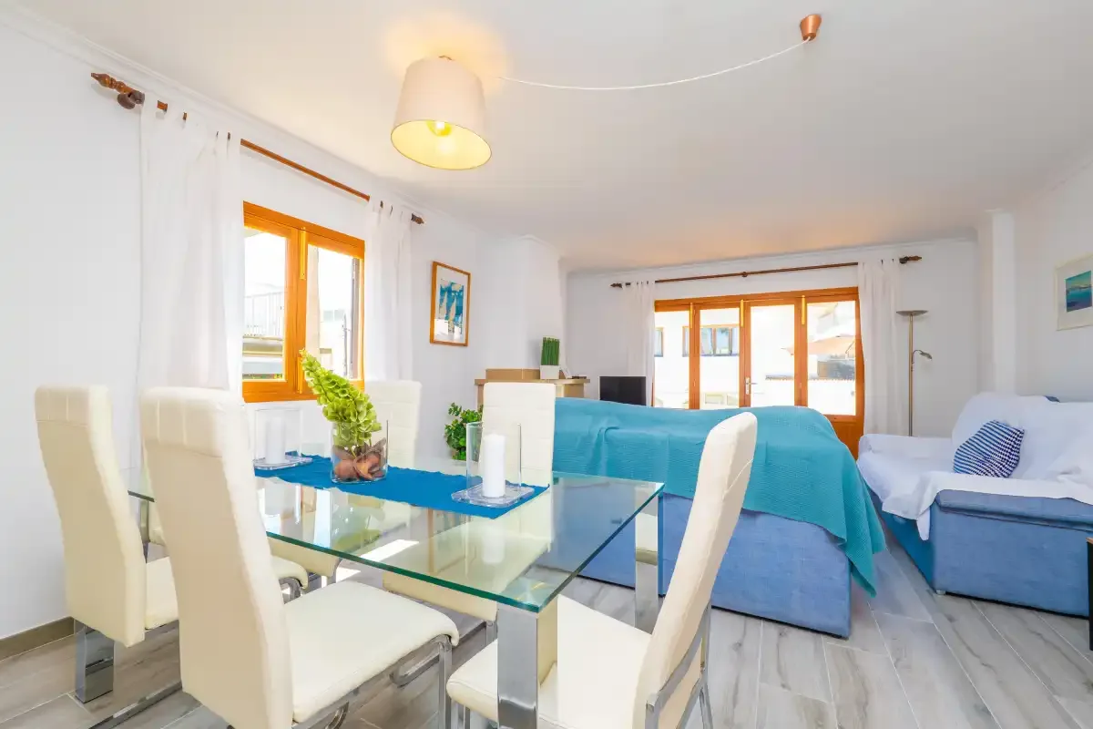 Una luminosa sala de estar y comedor con asientos azules y una mesa de vidrio.