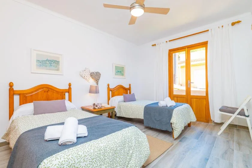 Un dormitorio luminoso con dos camas y una puerta acristalada con marco de madera.