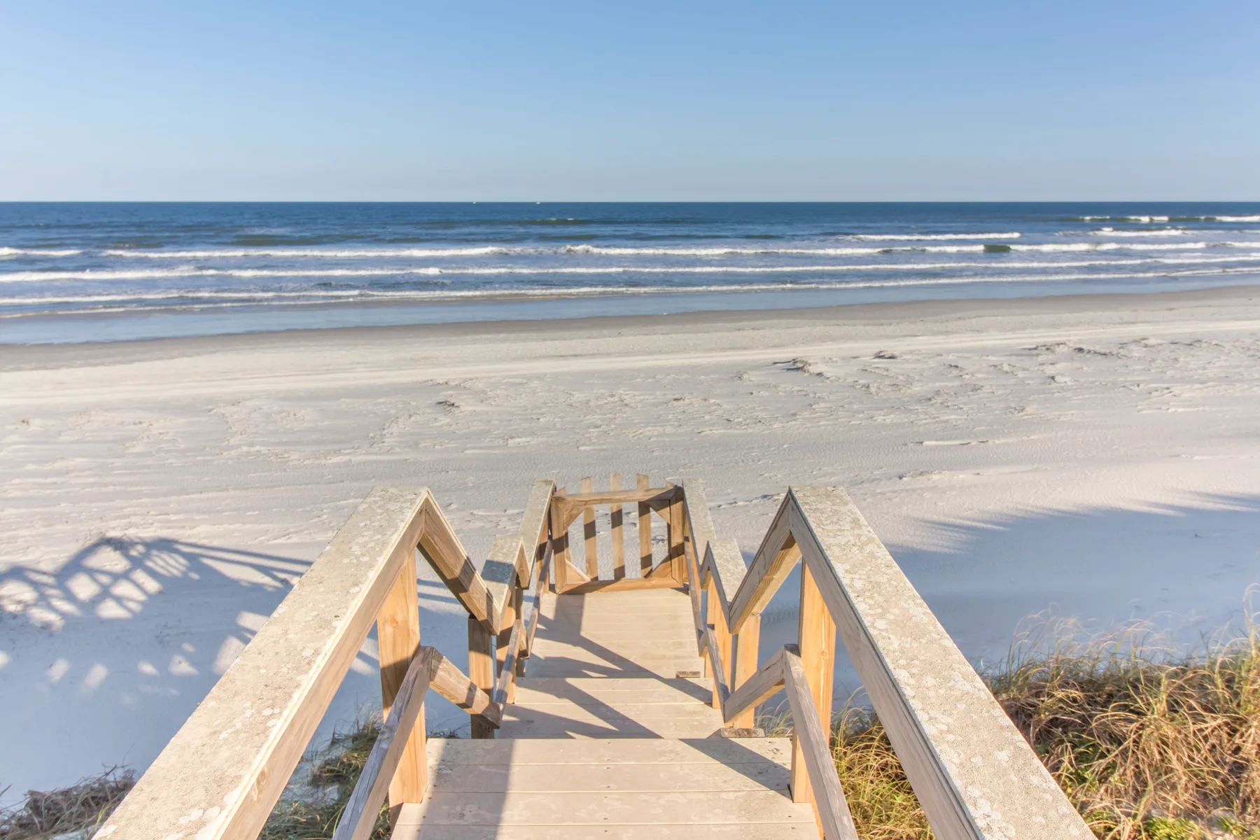 A wooden beach walkway leads across the sand toward the ocean.