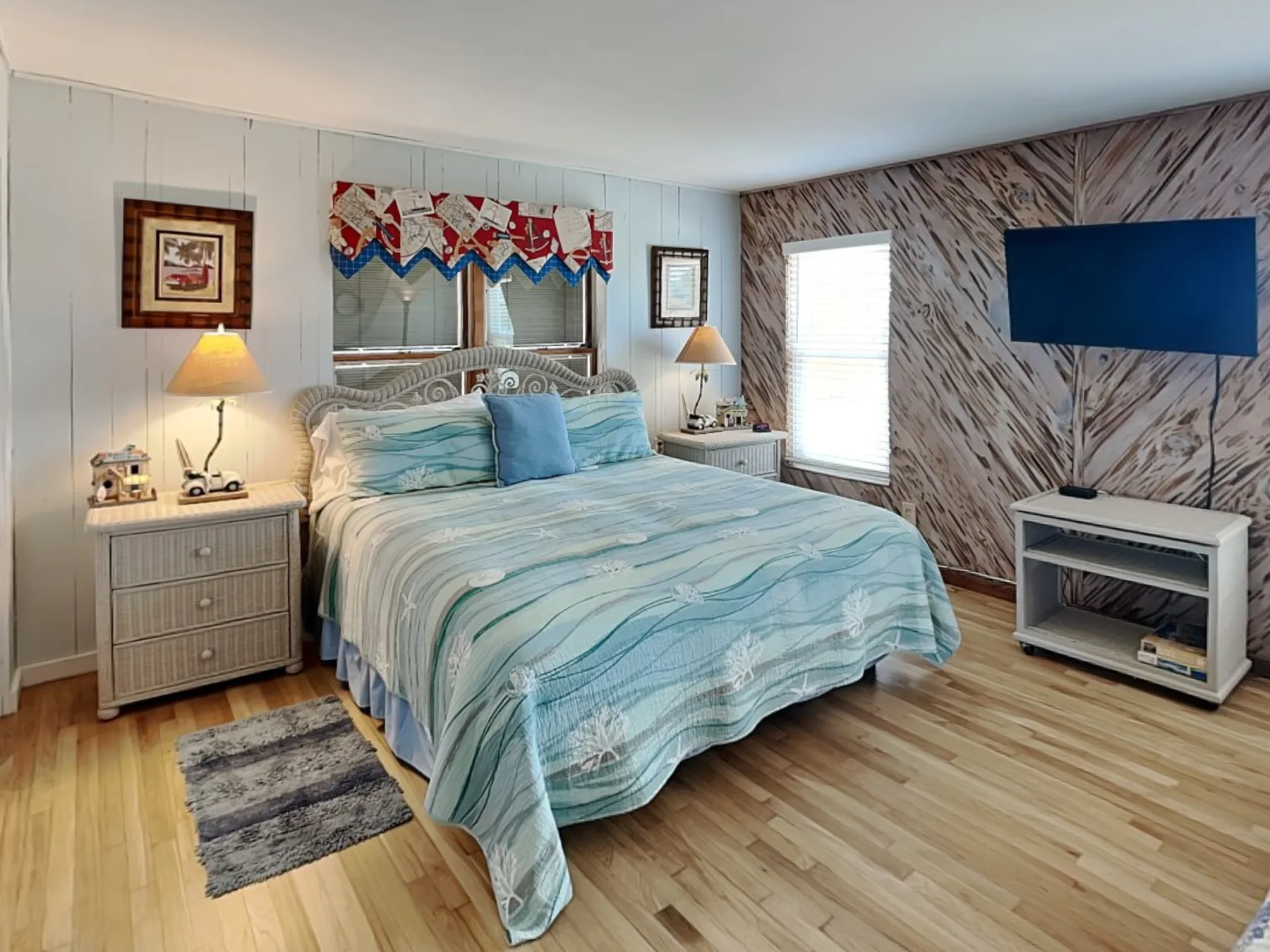 Un dormitorio con una cama bien tendida y un televisor montado en la pared.