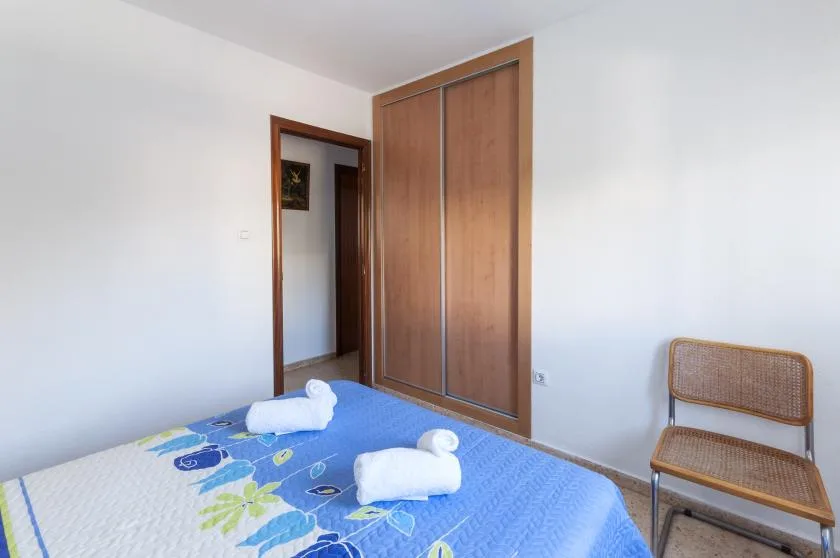 Un dormitorio con una cama cubierta con ropa de cama azul y un armario de madera.