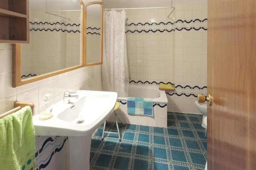 Un baño con azulejos, lavabo, bañera y cortina de ducha.