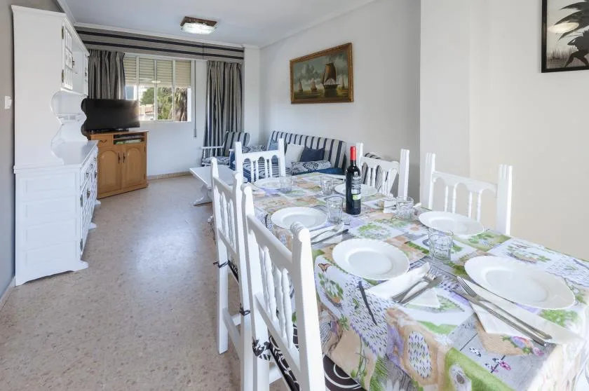 Comedor con una mesa larga puesta y una ventana al fondo.