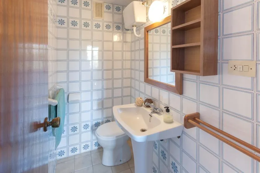Un baño alicatado con lavabo, inodoro y espejo en la pared.