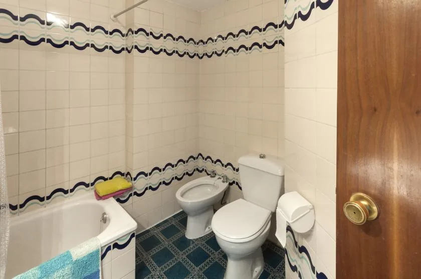 Un baño alicatado con bañera e inodoro.